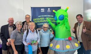City officials of Roswell, NM, airport employees and members of the Roswell Air Center Airport Advisory Council take a photo with an alien mascot celebrating the inaugural flight.