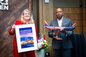 DEN CEO Phil Washington and Southwest Speaker holding commemorative poster and model airplane for the airline's 20th Anniversary at DEN.
