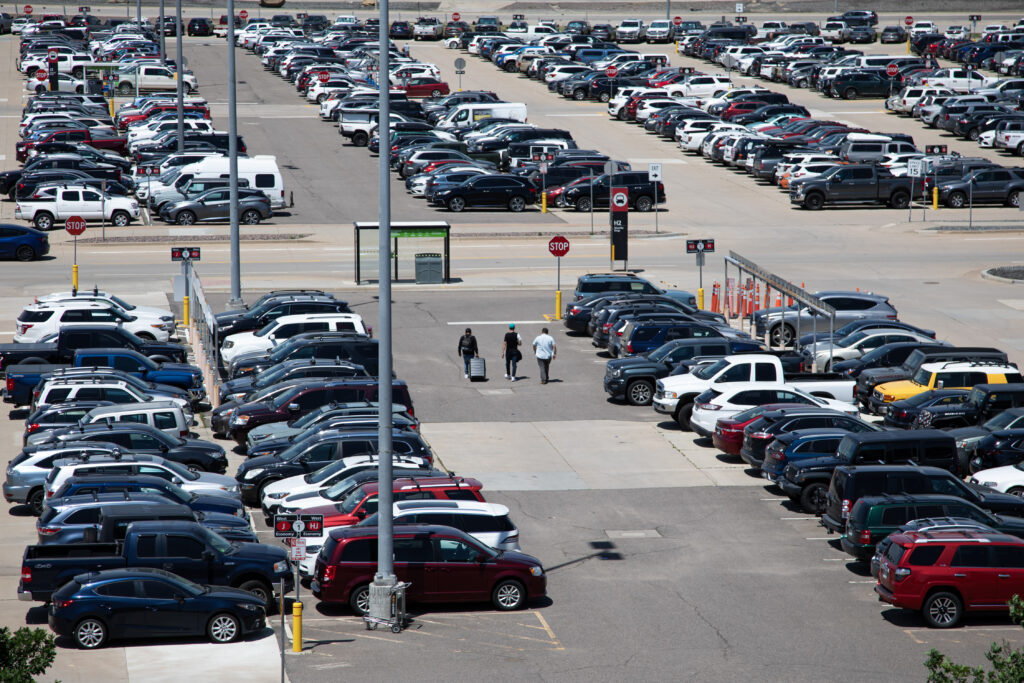 Travelers move through the West Economy parking lot